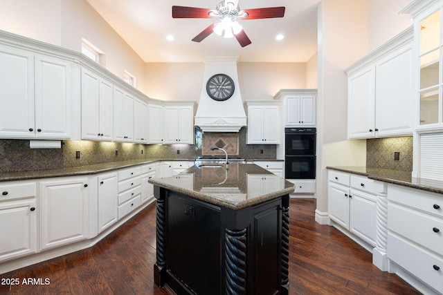 kitchen featuring dark stone counters, ceiling fan, decorative backsplash, white cabinets, and dobule oven black