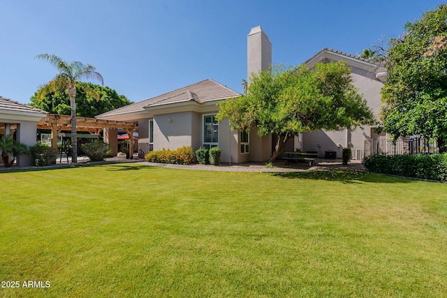 rear view of house featuring a yard, a chimney, stucco siding, and a pergola