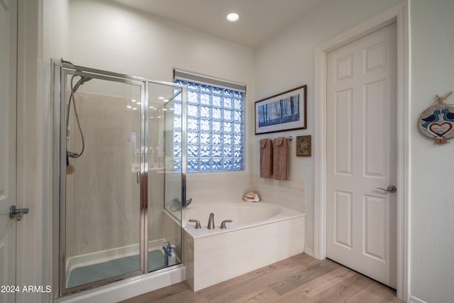 bathroom featuring wood-type flooring and shower with separate bathtub