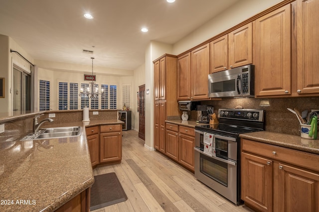 kitchen with sink, backsplash, a chandelier, decorative light fixtures, and appliances with stainless steel finishes