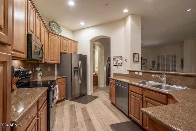 kitchen with backsplash, sink, stainless steel appliances, and light hardwood / wood-style flooring