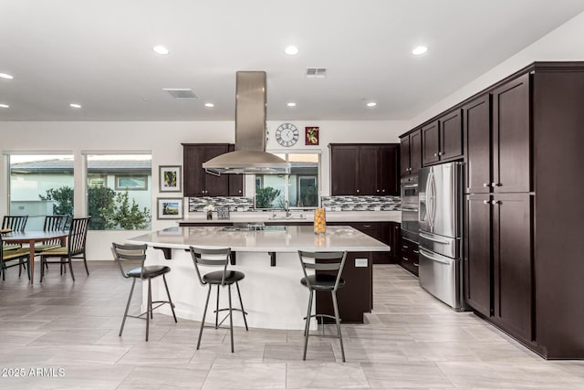 kitchen with appliances with stainless steel finishes, a center island, a breakfast bar area, and island range hood