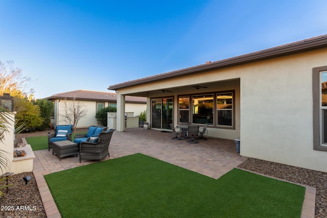 exterior space with an outdoor hangout area, a lawn, ceiling fan, and a patio area