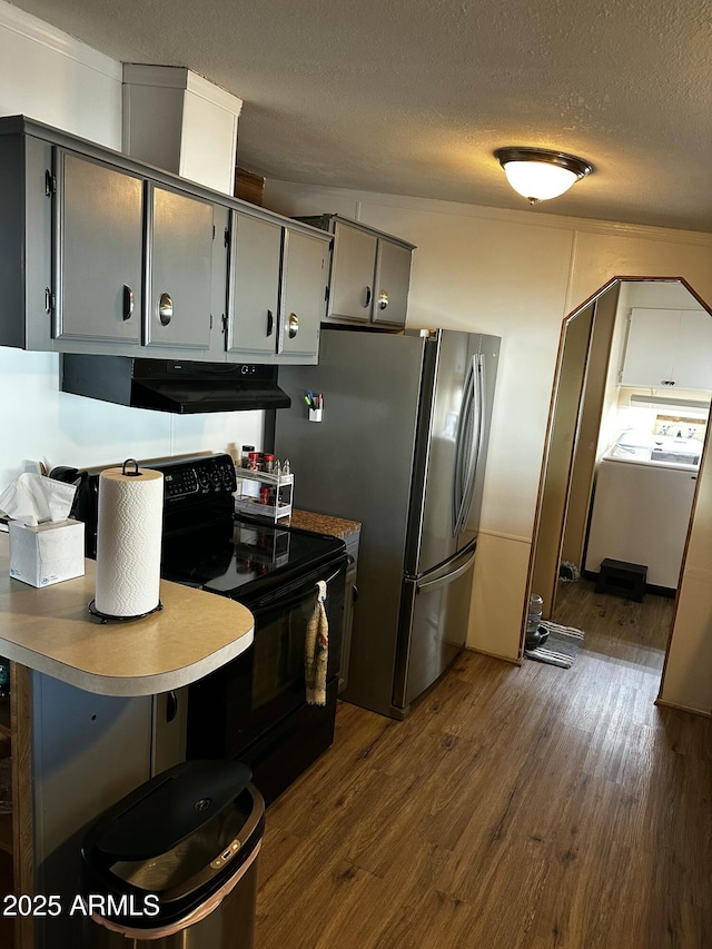 13638 S Sage Brush Dr, Mayer, AZ 86333 - kitchen with black range with electric stovetop, under cabinet range hood, dark wood-type flooring, a textured ceiling, and washer / clothes dryer