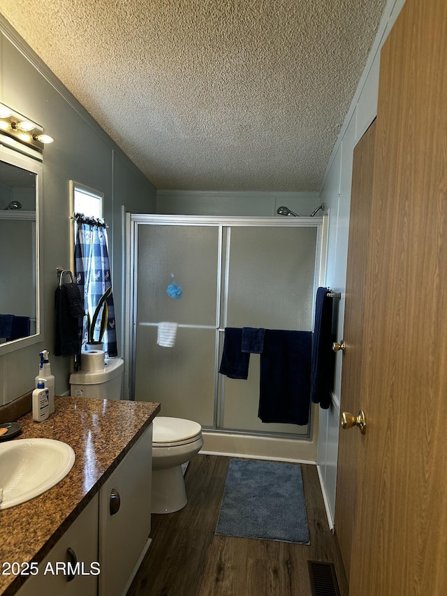 13638 S Sage Brush Dr, Mayer, AZ 86333 - bathroom featuring toilet, a textured ceiling, vanity, wood finished floors, and a stall shower
