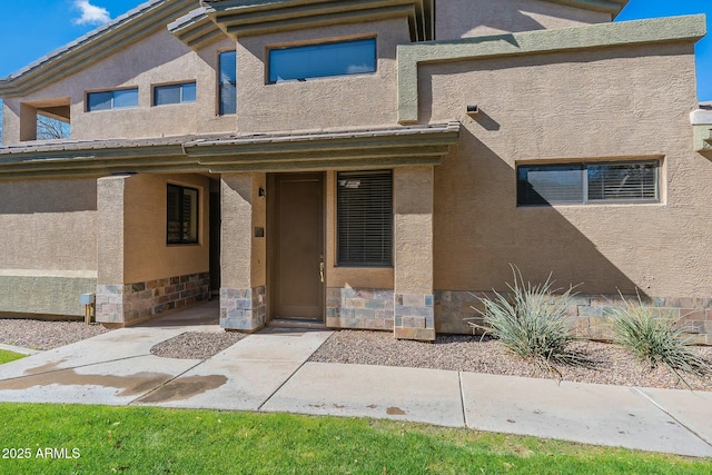 entrance to property with stone siding and stucco siding