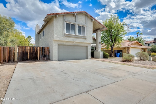 view of front of house featuring stucco siding, an attached garage, concrete driveway, and fence