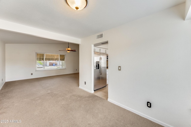 spare room with visible vents, light colored carpet, baseboards, and ceiling fan