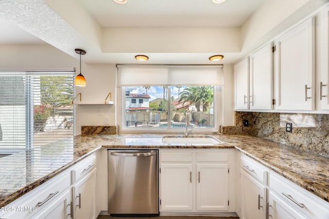 kitchen with stainless steel dishwasher, decorative backsplash, white cabinets, and a sink