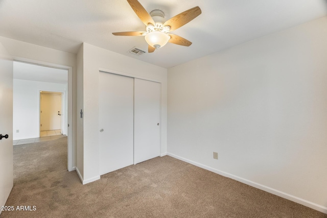 unfurnished bedroom with baseboards, visible vents, ceiling fan, a closet, and light carpet