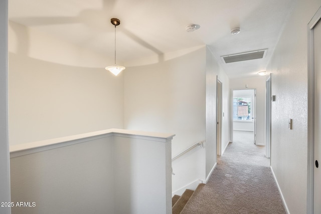 hallway featuring baseboards, carpet floors, and an upstairs landing