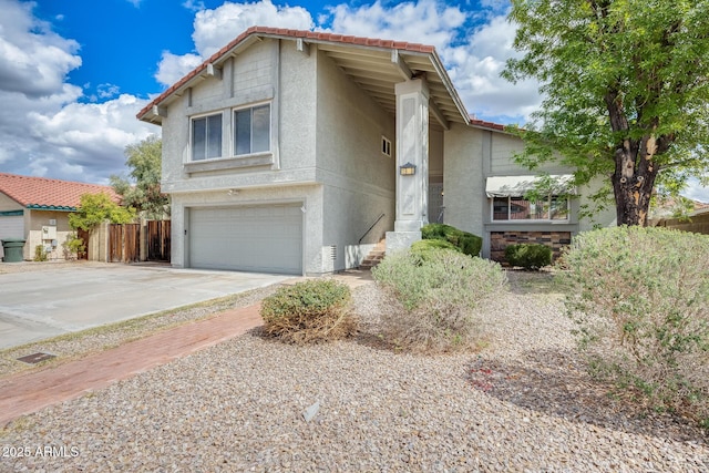 view of front facade with fence, driveway, stucco siding, a garage, and a tile roof