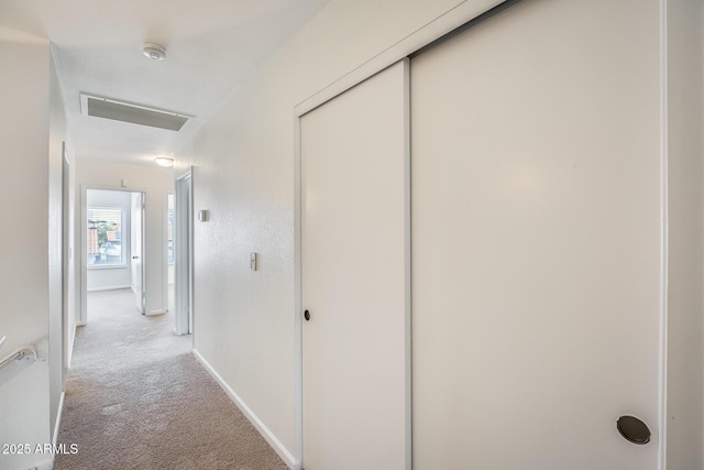 corridor with visible vents, baseboards, and light colored carpet