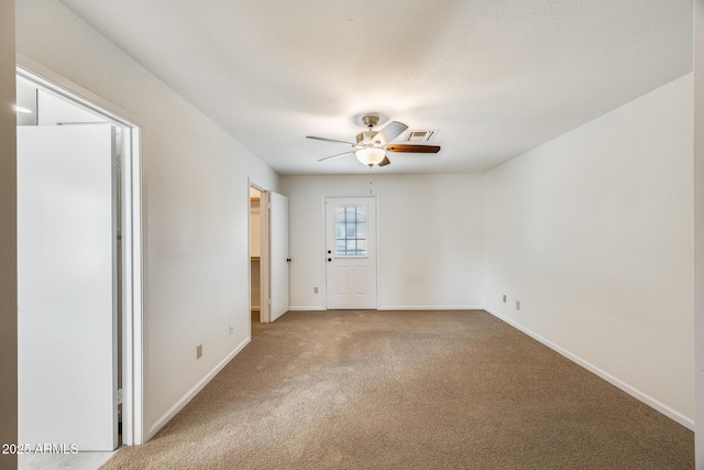 unfurnished room with visible vents, carpet floors, baseboards, and a ceiling fan