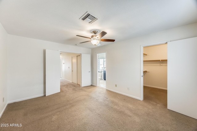 unfurnished bedroom with a spacious closet, visible vents, carpet flooring, and baseboards