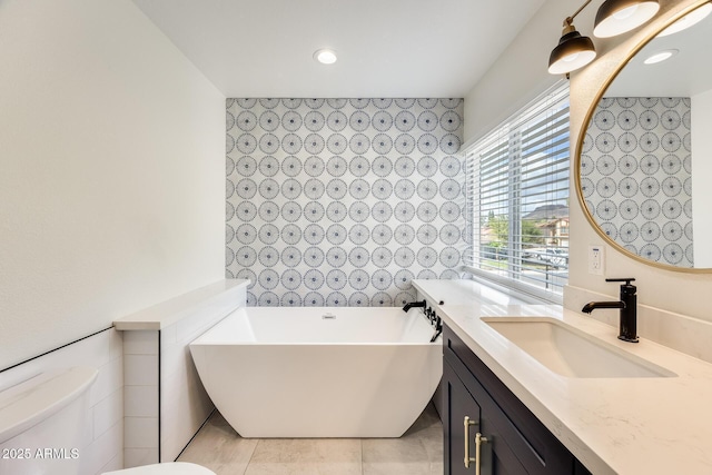 bathroom featuring recessed lighting, a freestanding tub, toilet, and vanity