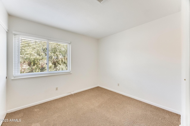 spare room with baseboards and light carpet