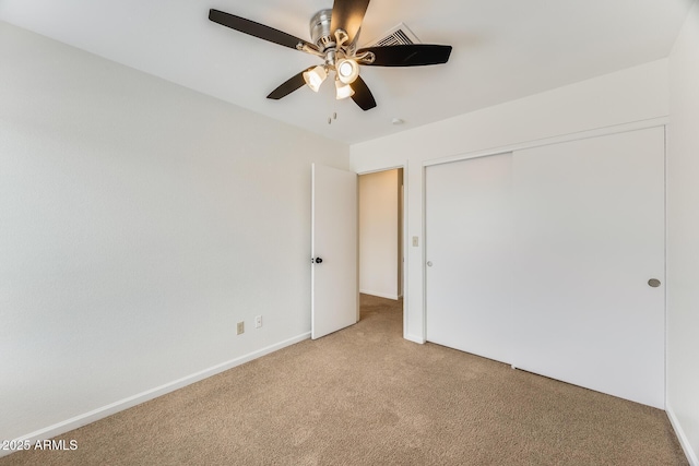 unfurnished bedroom with a closet, light carpet, baseboards, and ceiling fan