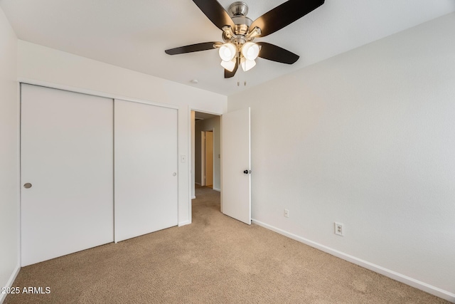 unfurnished bedroom featuring a closet, baseboards, light colored carpet, and a ceiling fan