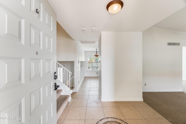 hallway with visible vents, baseboards, stairs, light tile patterned floors, and light carpet