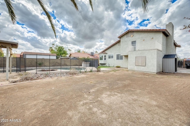 back of house featuring a fenced backyard, a fenced in pool, and stucco siding