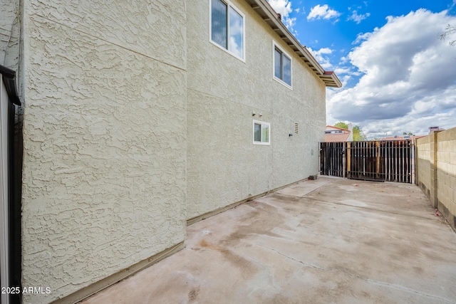 exterior space featuring a patio, fence, and stucco siding