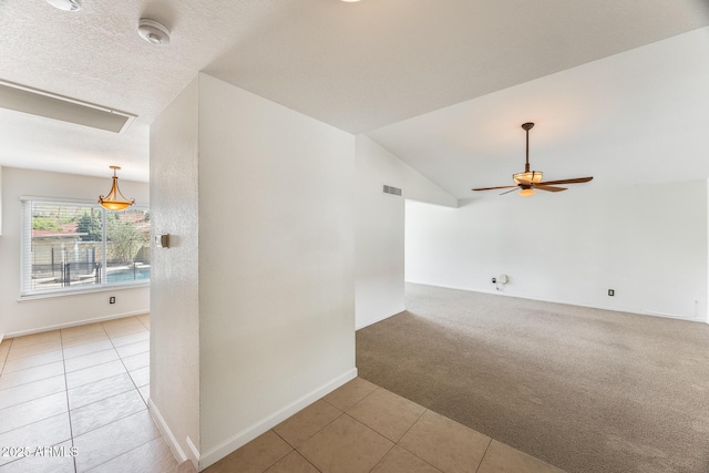 empty room with light tile patterned floors, a ceiling fan, visible vents, lofted ceiling, and light colored carpet