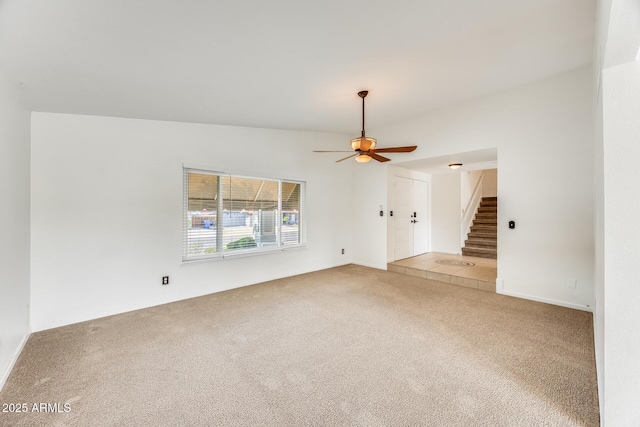 unfurnished room featuring light colored carpet, stairs, and a ceiling fan