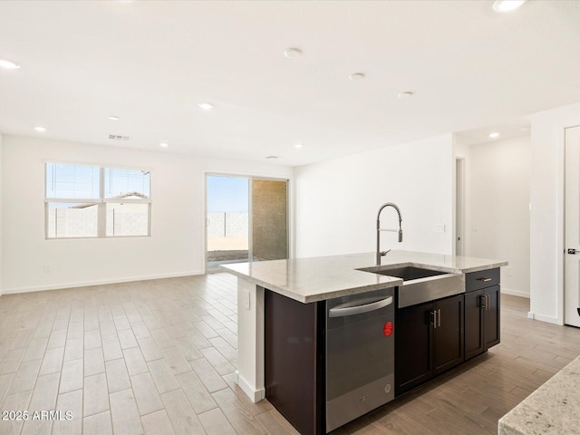 kitchen with a sink, light wood-style flooring, stainless steel dishwasher, and open floor plan