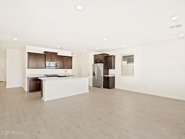 kitchen with light wood-type flooring, stainless steel appliances, open floor plan, and a sink