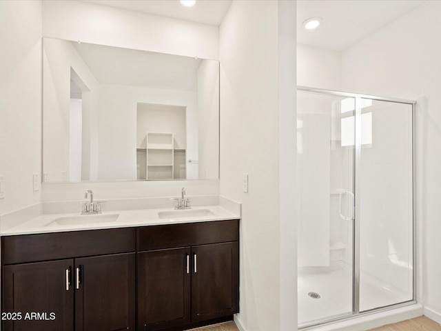 bathroom featuring double vanity, a stall shower, and a sink