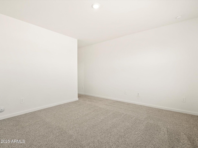 empty room featuring baseboards and light carpet