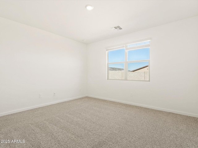 carpeted spare room featuring visible vents and baseboards