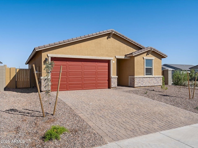 ranch-style house featuring stucco siding, a tile roof, decorative driveway, stone siding, and an attached garage