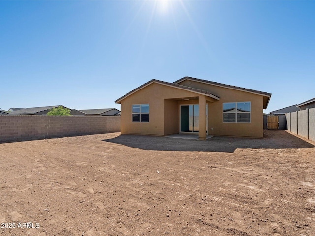 back of house with a fenced backyard and stucco siding