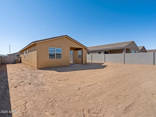 rear view of house featuring central air condition unit, a fenced backyard, and stucco siding