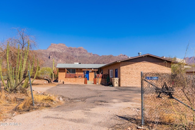 single story home with a mountain view, brick siding, and dirt driveway