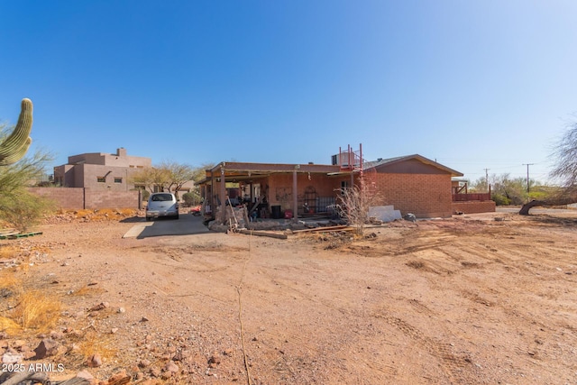 rear view of house featuring brick siding and dirt driveway