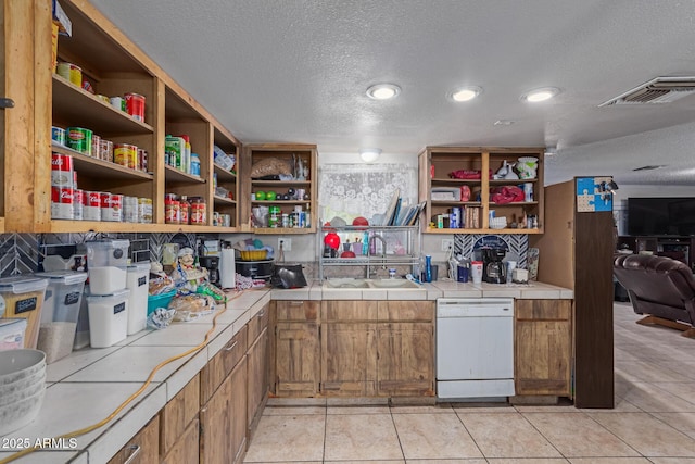 kitchen with visible vents, open shelves, a sink, dishwasher, and tile counters