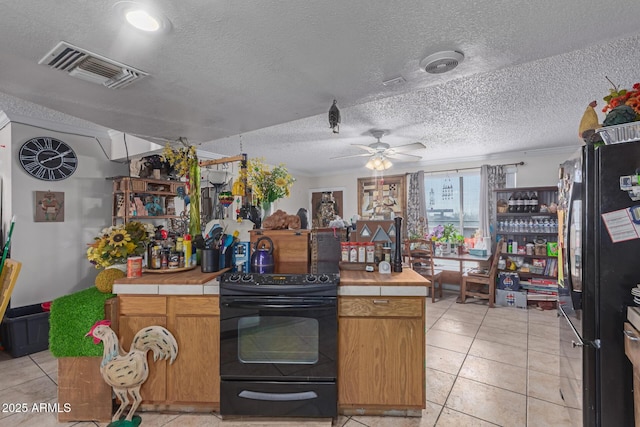 kitchen with visible vents, black appliances, tile countertops, light tile patterned floors, and a textured ceiling