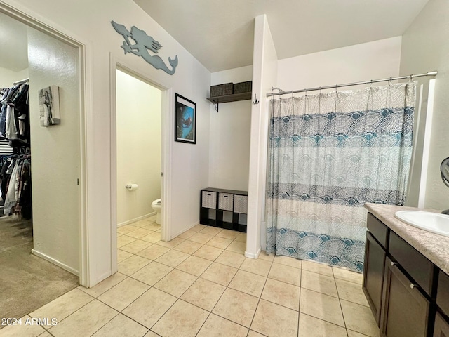 bathroom with walk in shower, vanity, tile patterned flooring, and toilet