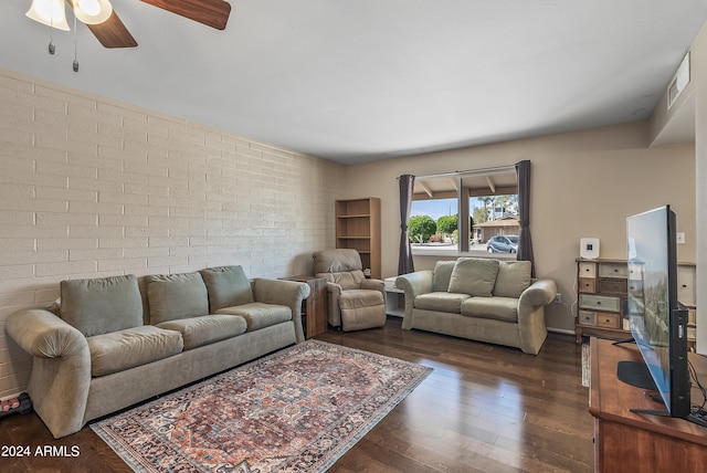 living room with brick wall, ceiling fan, and dark hardwood / wood-style flooring