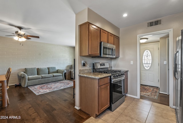 kitchen with light hardwood / wood-style floors, stainless steel appliances, and brick wall