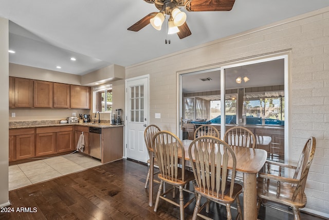 dining room with sink, brick wall, light wood-type flooring, and ceiling fan