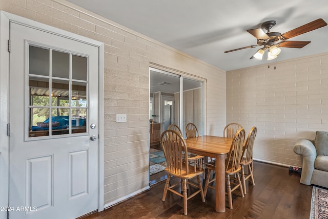 dining room featuring brick wall, dark wood-type flooring, and ceiling fan