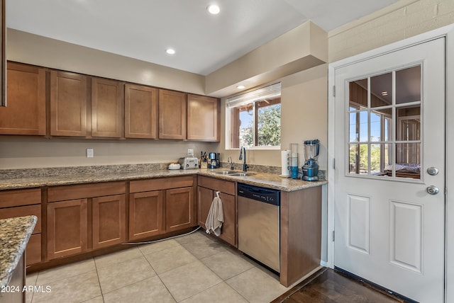 kitchen with sink, light stone counters, light tile patterned flooring, and dishwasher