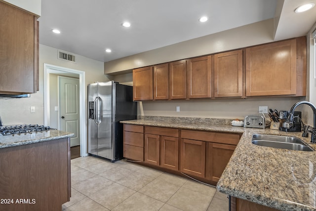 kitchen with sink, light tile patterned floors, light stone counters, and stainless steel fridge with ice dispenser