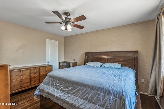 bedroom featuring dark hardwood / wood-style floors, brick wall, and ceiling fan