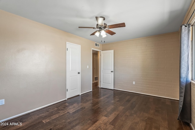 unfurnished bedroom with dark hardwood / wood-style floors, brick wall, and ceiling fan