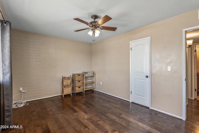 interior space featuring ceiling fan, brick wall, and dark hardwood / wood-style flooring